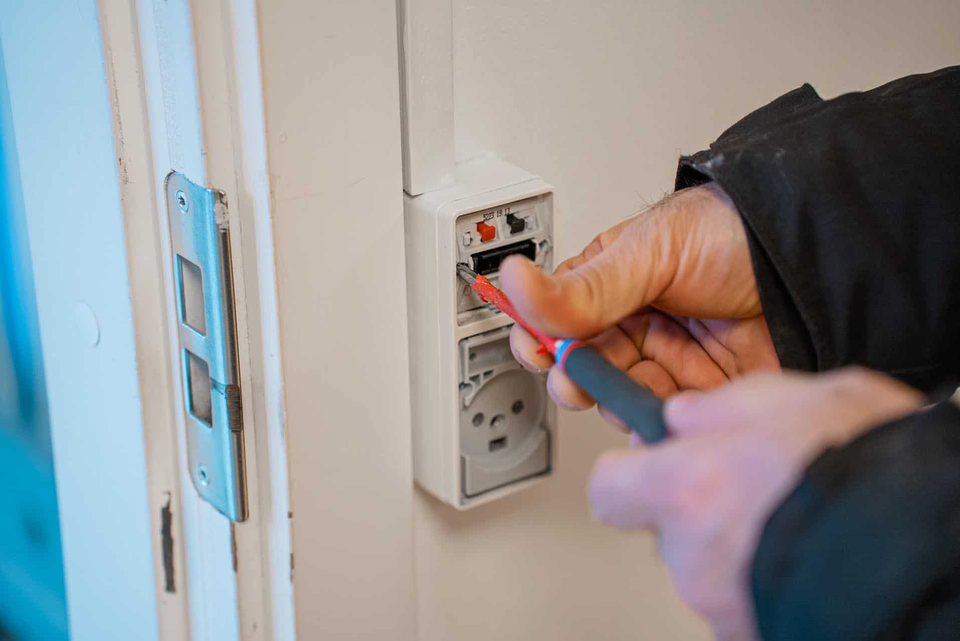 Elektriker trækker ledninger i stikdåse